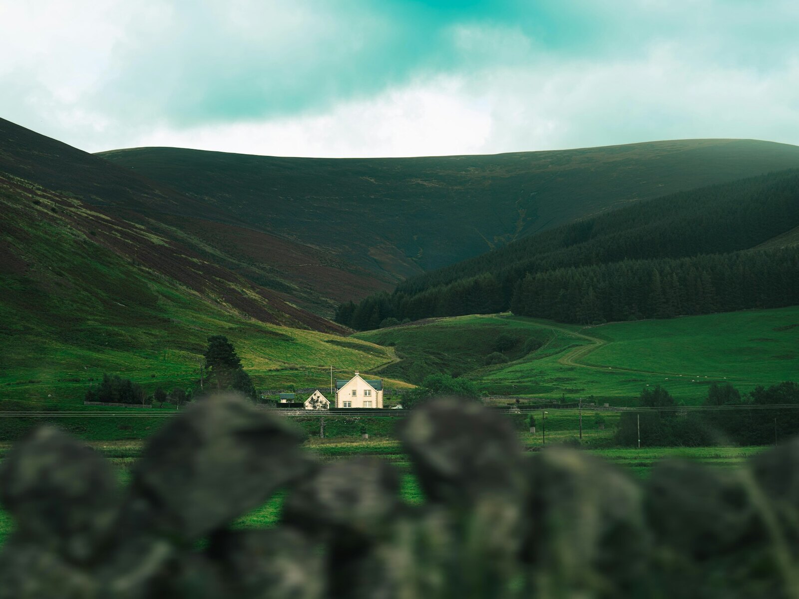 A stone cottage in the Peak District with green hills behind